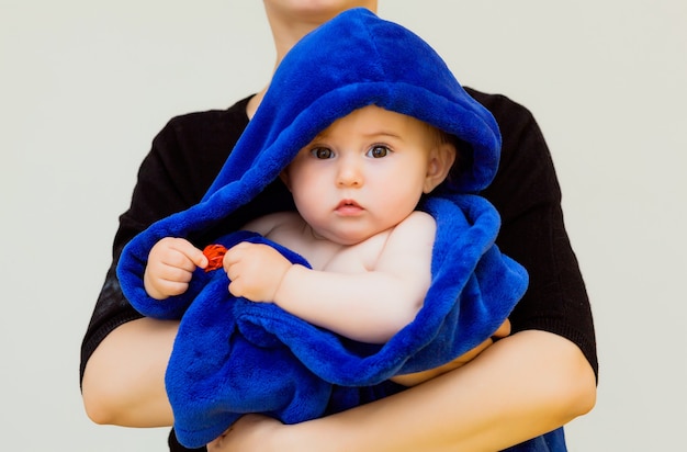엄마는 파란 수건으로 덮인 어린 아기를 안아줍니다. 목욕 후 아기와 어머니