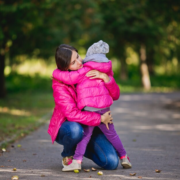 mom hugs her little daughter in the park