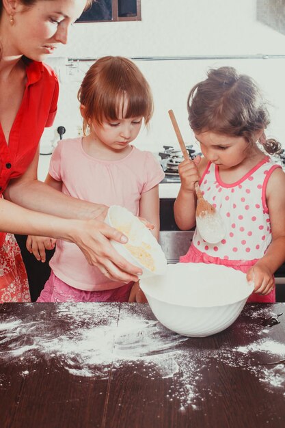 Mom is baking cookies with her kids at home kitchen