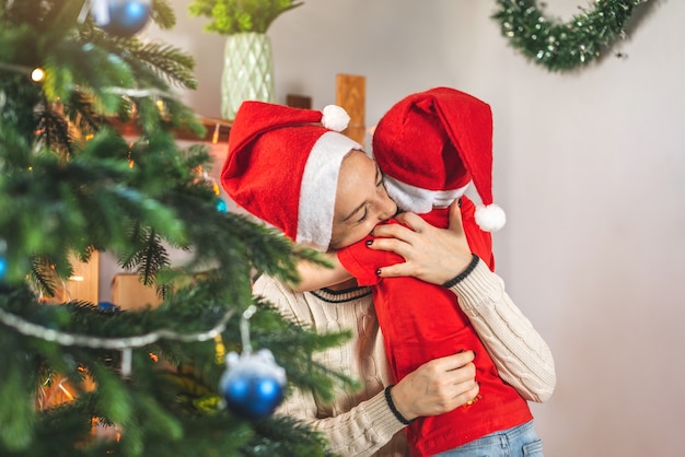 Mom is helping her child son decorate the Christmas tree