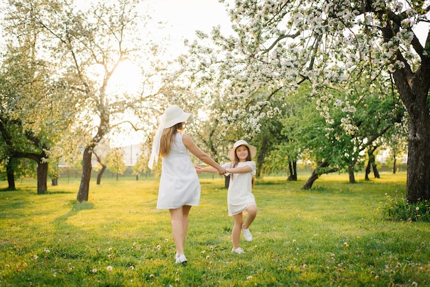 엄마는 귀여운 딸과 함께 봄 정원을 돌고 있다 엄마와 아기는 봄 꽃에서 즐거운 시간을 보내고 있다