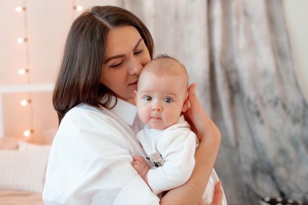 Mom keeps the baby at home in the bedroom kisses