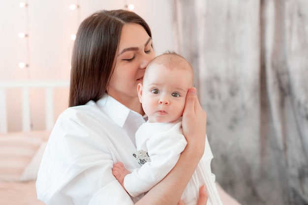 Mom keeps the baby at home in the bedroom kisses