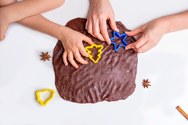 Photo mom and kid son cut out with molds dough for cookies or gingerbread. cooking dough for christmas baking.