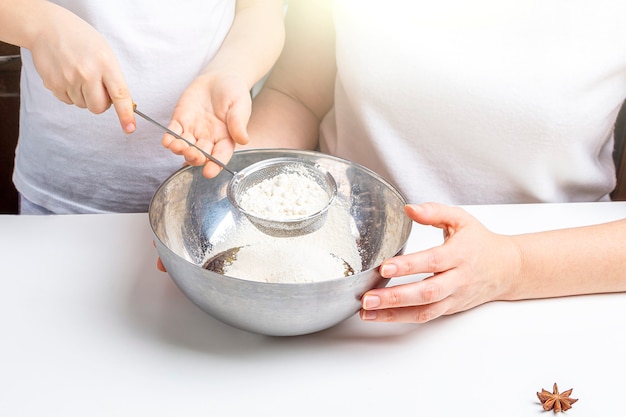 Mom and kid son kneading dough for sweet pastries, cookies. Cooking dough for baking in home kitchen. Preschooler skills, little helper. Family pastime. Adding ingredients