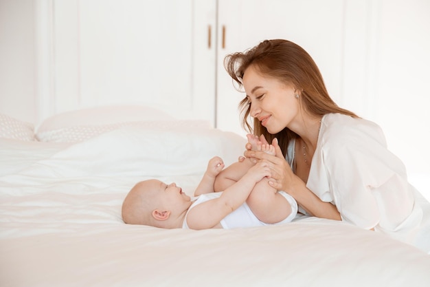 Mom kisses the baby's legs at home in the bedroom