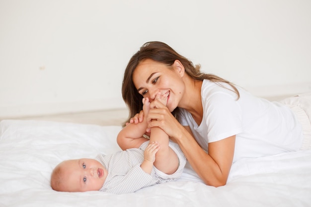 Photo mom kisses babys legs at home in the bedroom