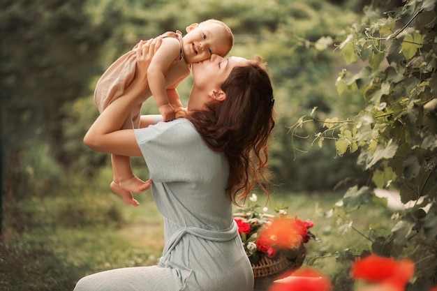 Mom kisses her baby boy in a green garden