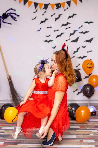 Mom kisses her daughter at home Halloween party