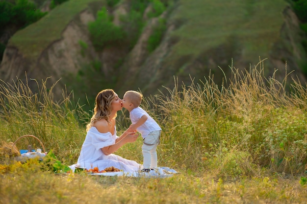 Mom kisses her son. Mothers Day. Mother and son. The child kisses the mother. Woman in a field with a child. Children Protection Day. Beautiful nature with people