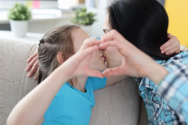 Mom kisses little daughter together show heart gesture