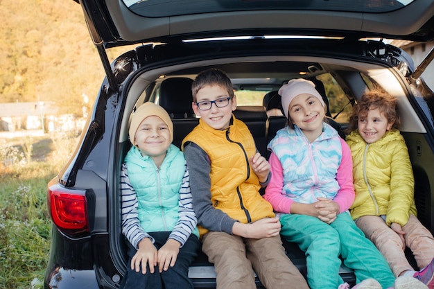 Mom and little boy sitting in hatchback car with mountain background