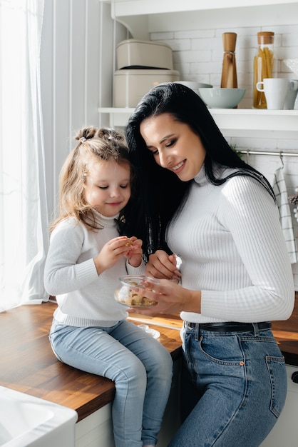 Mom and Little Daughter cook in the kitchen and play. Family, happiness.