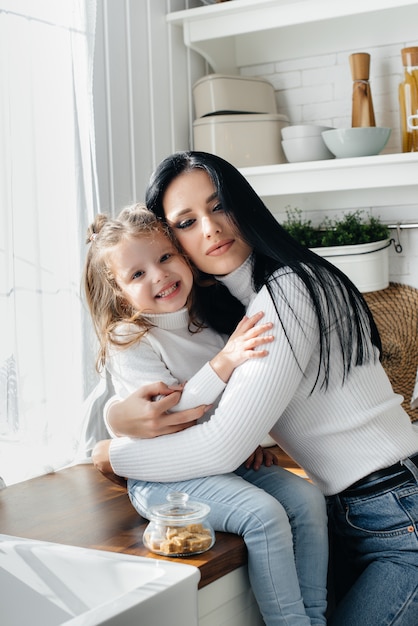 Mom and Little Daughter cook in the kitchen and play. Family, happiness.