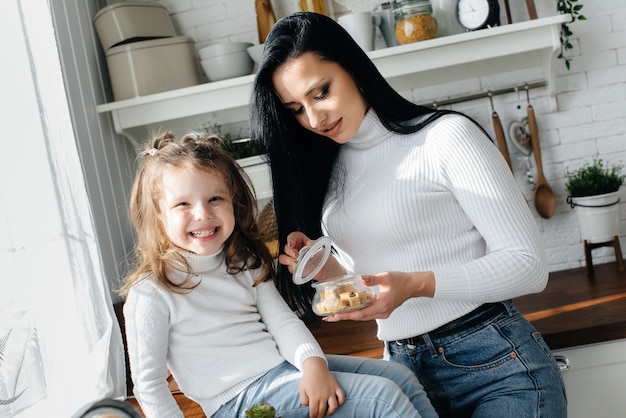 Mom and Little Daughter cook in the kitchen and play. Family, happiness.