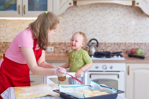 Photo mom and little daughter cook pies in the kitchen at home