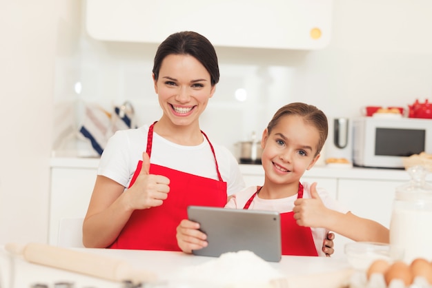 Mom and little daughter cook together in the kitchen at home.