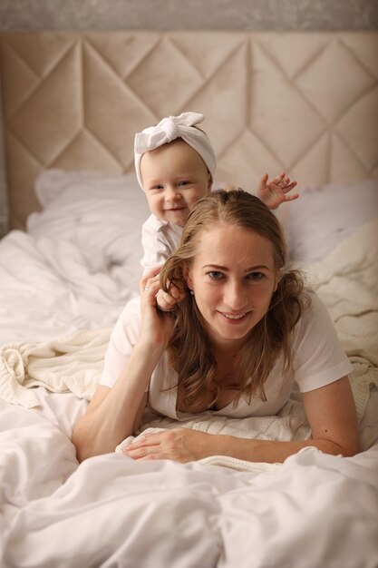 mom and little daughter cuddle on a white sheet motherhood