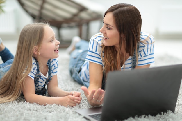 엄마와 어린 딸이 노트북과 기술을 보면서 무언가에 대해 토론하고 있습니다.