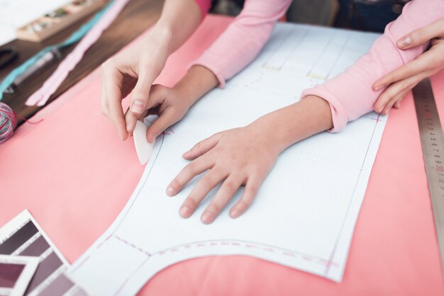 Mom and little daughter together sew clothes.