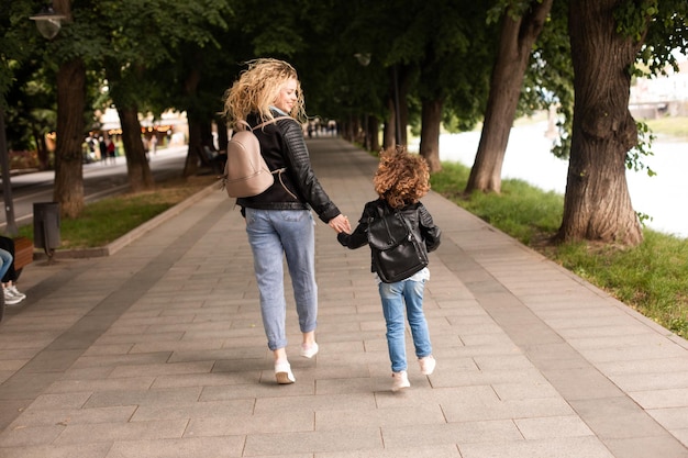 The mom and little girl walk together along the waterfront