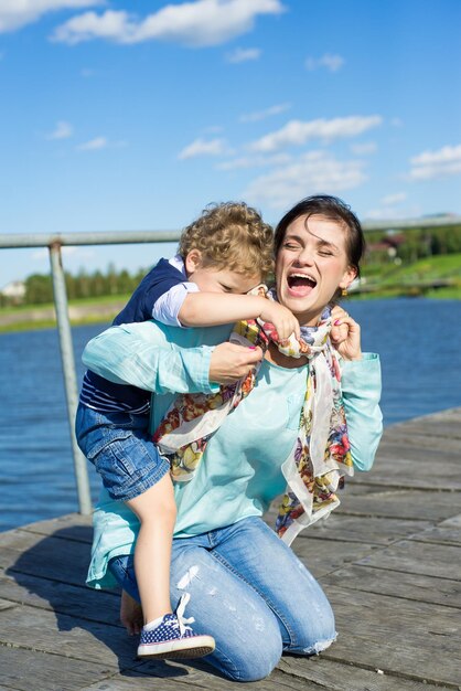 Mom and little son walk in the park and have fun on a sunny summer day