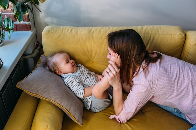 Mom plays at home with a small child on the couch have fun