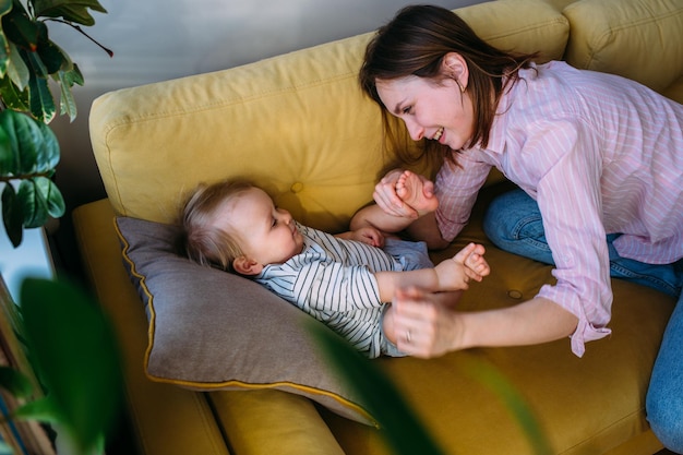 Mom plays at home with a small child on the couch have fun