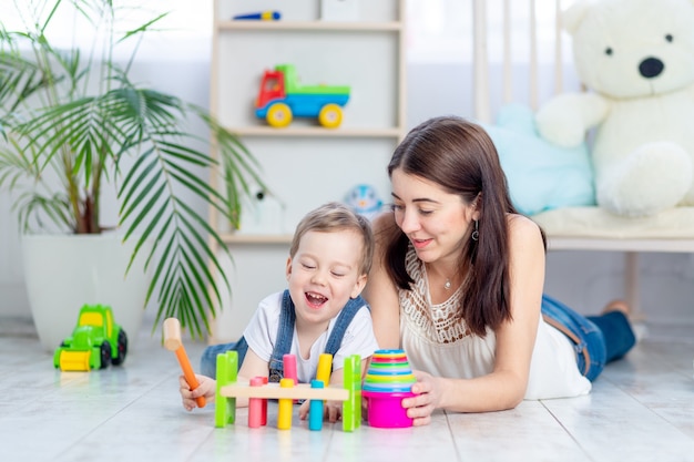 Mom plays with the child at home in the educational toys in the children's room. A happy, loving family.