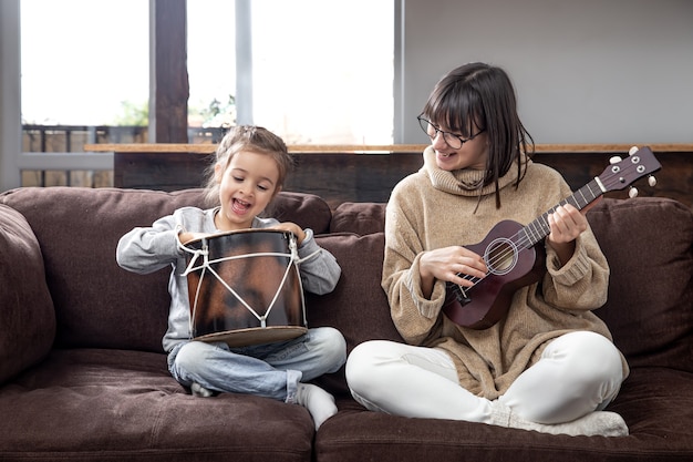 Мама играет с дочерью дома. уроки игры на музыкальном инструменте. развитие детей и семейные ценности. концепция детской дружбы и семьи.