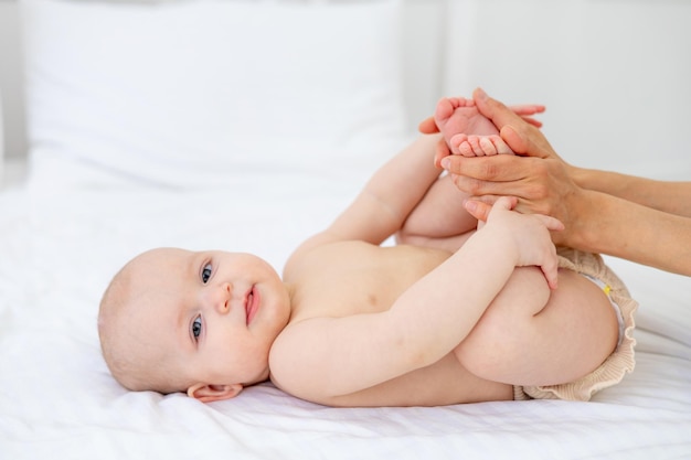 Mom's hands hold the baby in diapers or does foot massage love mother's care for the baby motherhood