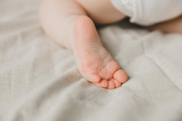 Mom's hands hold the baby's legs in on a cotton bed hygiene and care and care for the newborntoddler's heel