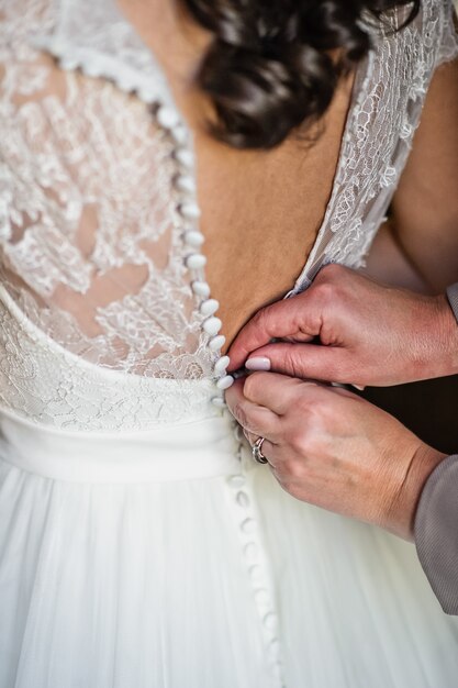 Mom's hands tie the bride's dress