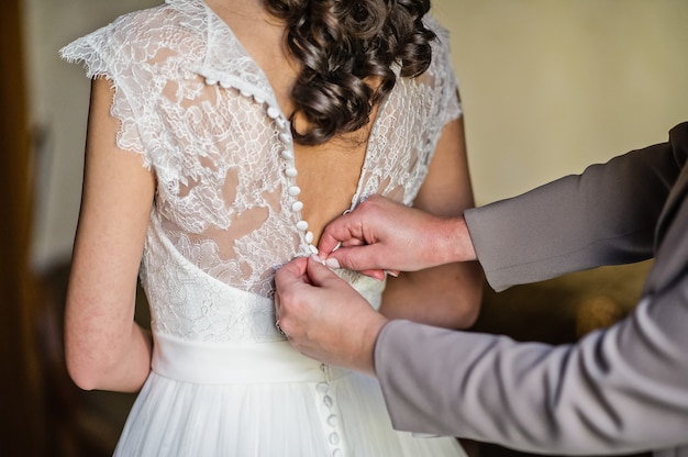 Mom's hands tie the bride's dress