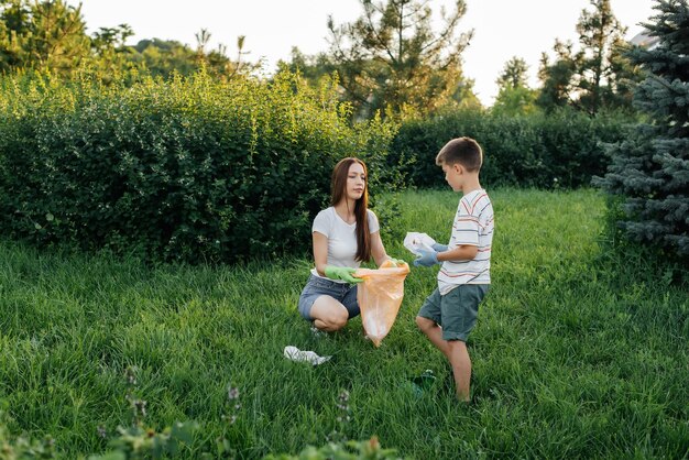 Mom and son are cleaning garbage in the park at sunset Environmental care waste recycling