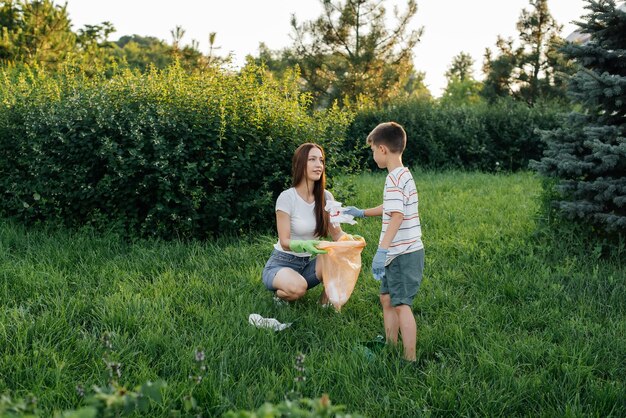 Mom and son are cleaning garbage in the park at sunset Environmental care waste recycling