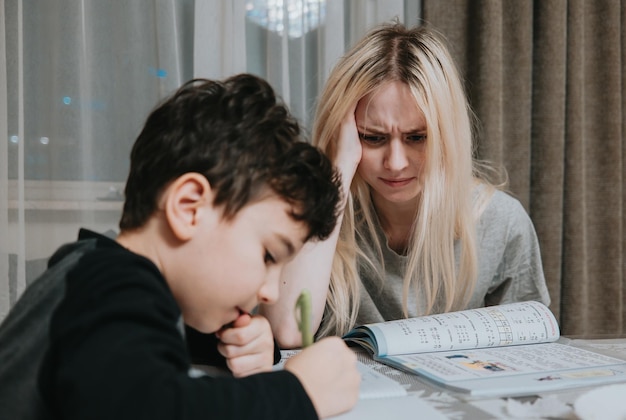 Foto mamma e figlio stanno facendo i compiti. la sorella aiuta il fratello a risolvere la matematica a casa. foto di alta qualità.