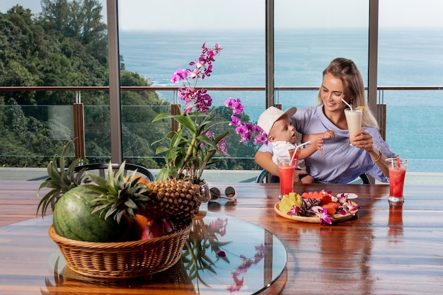 Mom and son are drinking freshly squeezed juices from tropical fruits