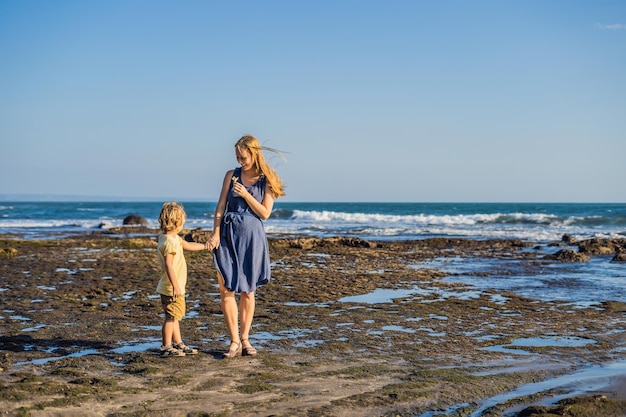 Mom and son are walking along the cosmic Bali beach.. Portrait travel tourists - mom with kids. Positive human emotions, active lifestyles. Happy young family on sea beach