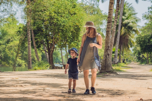 Mom and son are walking on the forest road.