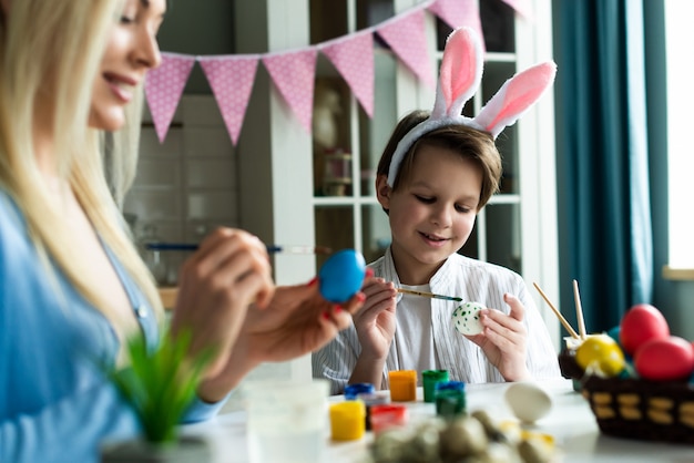 Foto mamma e figlio decorano le uova di pasqua in cucina.