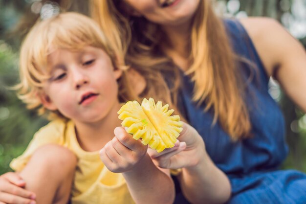 Mom and son had a picnic in the park. Eat healthy fruits - mango, pineapple and melon. Children eat healthy food.