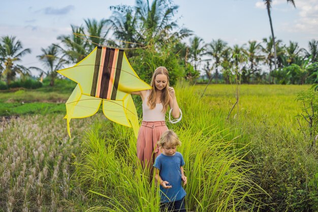 Mom and son launch a kite in a rice field in Ubud, Bali Island, Indonesia.