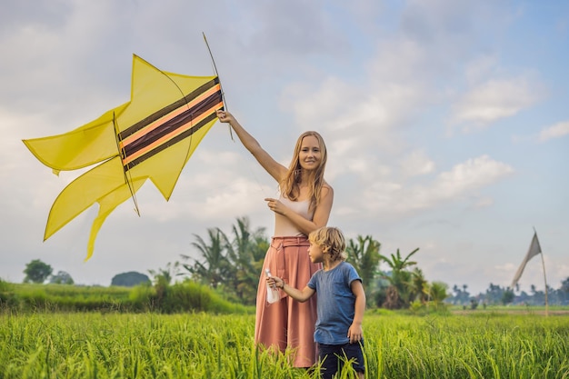 Mom and son launch a kite in a rice field in Ubud, Bali Island, Indonesia.