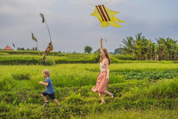 Mom and son launch a kite in a rice field in Ubud, Bali Island, Indonesia