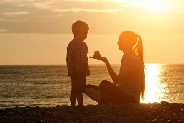 Mamma e figlio che giocano sulla spiaggia con pietre