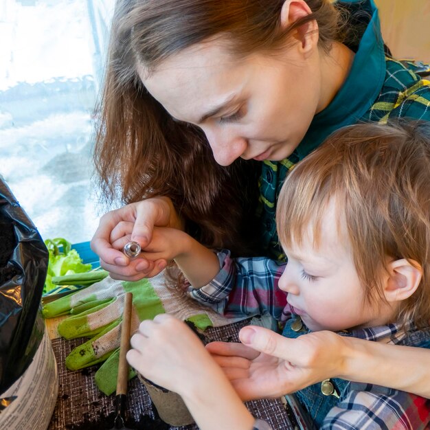 Mom and son prepare a hole and plant seeds in a peat pot