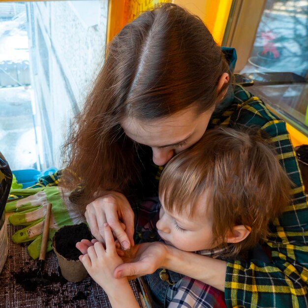 Mom and son prepare a hole and plant seeds in a peat pot