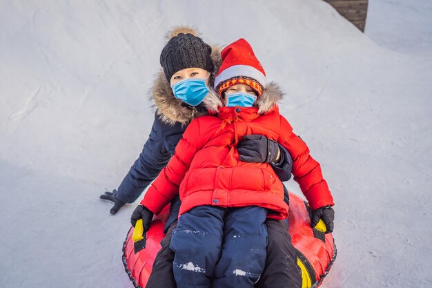 mom son ride on an inflatable winter sled tubing wear medical masks due to the COVID19 coronavirus Winter fun for the whole family