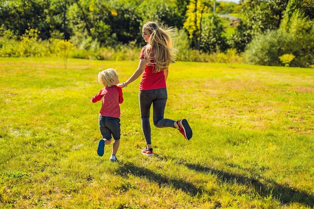 Mom and son run on the green grass Happy family in the park